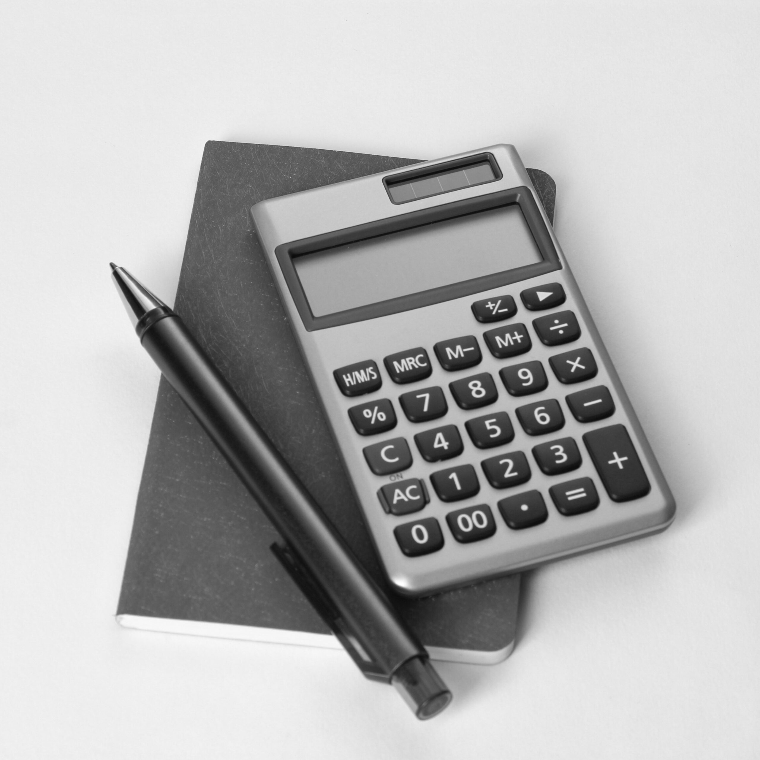 calculator and pen lying on top of a small notebook